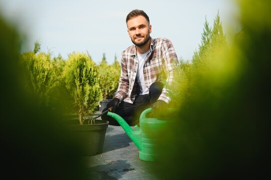 Male employee of garden shopping center inspects product. Department with potted plants, is preparing to advise clients