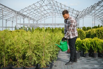 With watering can. Gardener is at work at daytime