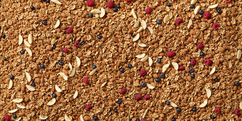 a flat lay background of healthy granola cereal mixed with fresh blueberries raspberries and sliced banana for breakfast.
