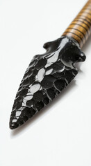 Close-up of sharp obsidian spearhead on glossy white background