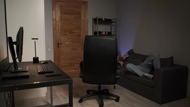 Young man finishing computer work rolling to sofa relaxing home authentic lifestyle