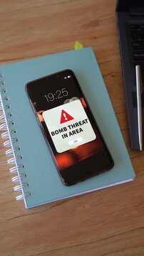 Bomb threath in area notification in smartphone screen. Vertical shot. 