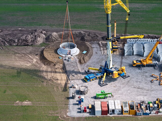 Large heavy-duty crane sets first parts for the tower of a wind turbine, building construction, wind energy, wind turbine, construction, crane, energy transition, sustainability, energy, renewable