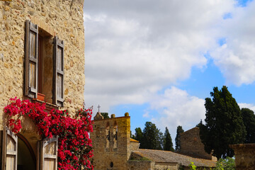 old mediterranean brick house with wooden shutters and red blooming bougainvillea, mediterranean...