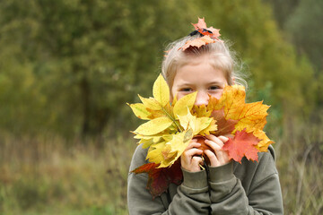 Portrait of a girl with a bouquet of autumn leaves in hand and on head