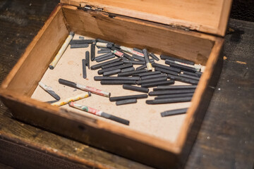 Naklejka premium Old slate writing sticks, historically used by schoolchildren for writing on slate boards. Antique slate writing sticks in wooden box.