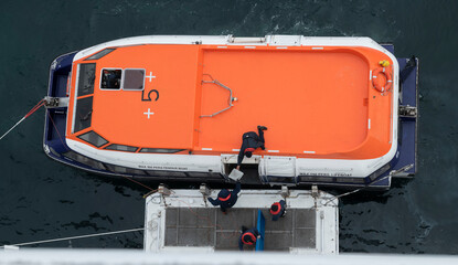 Tender boat next to a ship prepares to take passengers ashore.