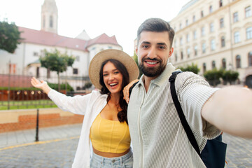 Obraz premium Happy European man and woman traveling together, recording video or taking selfie photos, walking around the city and showing off the sights and beautiful places
