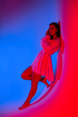 Model posed against a vibrant background showcasing dynamic red and blue lighting effects