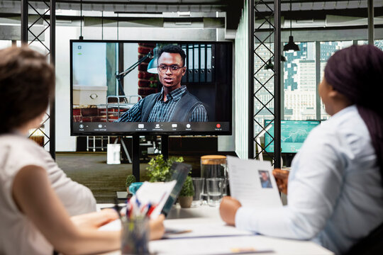 Recruiters team and male candidate engage in a video call discussion with webcam and high tech tools, reviewing the resume and assessing job search progress during a remote interview conference.