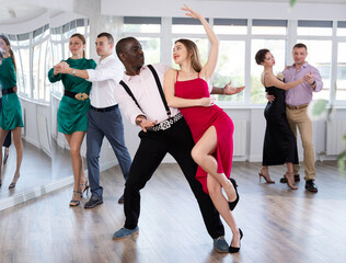 Fototapeta premium With unhurried music, woman with African man in couple spins to rhythm of waltz during lesson for novice students. Classes in mini-groups for those who want to learn dancing