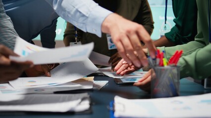 Diverse business team exchanging insights and forecasting diagrams in a late night meeting, reviewing financial data analytics and business intel. Advisory board collaboration. Camera A.