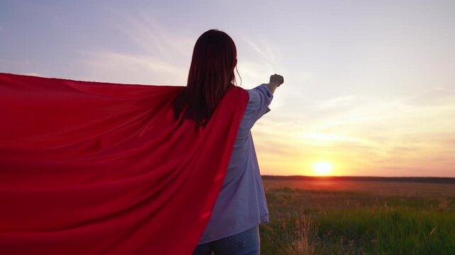 Beautiful superhero woman dream in nature. Teen girl playing in red cape in park sunset. Girl fantasy in red cape in park. Red superheroine costume. Superhero girl carnival at sunset. Fly imagination