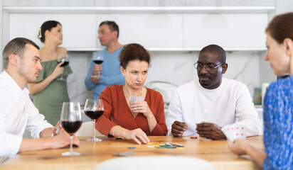 Friends who enjoy lively game of poker and pleasure of tasting fine wine in the comfort of their own home
