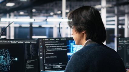 Technician arriving in data center office, coding with generative AI assistance. IT expert sitting at desk, starting work on artificial intelligence large language model solving tasks, camera A
