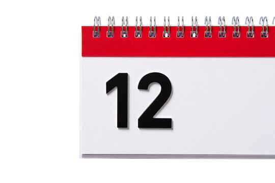 Close up of a spiral bound desk calendar showing the number twelve on a white page isolated on transparent background