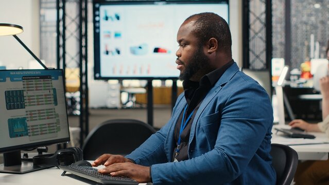 African american consultant engaged in planning and analysis with computer results to create strategy reports for shareholders. Working on innovation, objectives alignment and growth. Camera B.