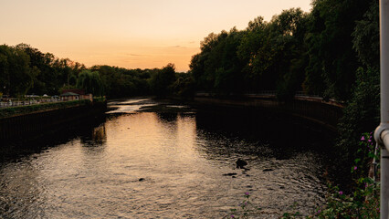 A breathtaking golden hour sunset with vibrant colors reflecting perfectly on the calm water near a historic lock and dam. This peaceful scene embodies tranquility and the beauty of nature's cycles.