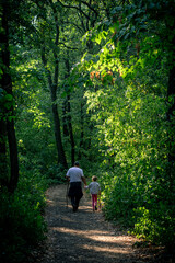 Grandpa and his grandkid are walking through the woods