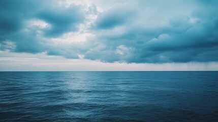 Vast expanse of dark blue sea meeting a sky of stormy clouds