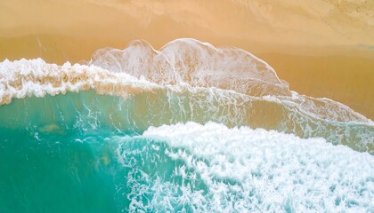 High-angle view of turquoise waves crashing on a light beige sandy beach, displaying foamy white crests and vibrant colors.