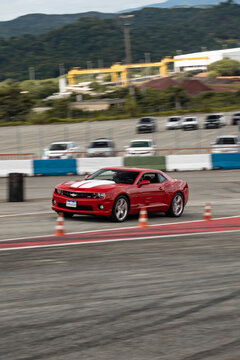Red Chevrolet Camaro at an autocross event, Panning shot of an american muscle car in action.

