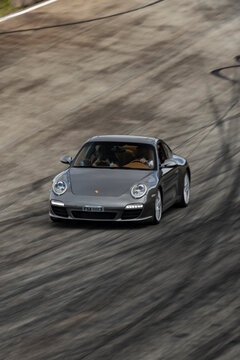 Grey Porsche 911 cornering at speed on a racetrack, Dynamic panning shot of a german sports car.

