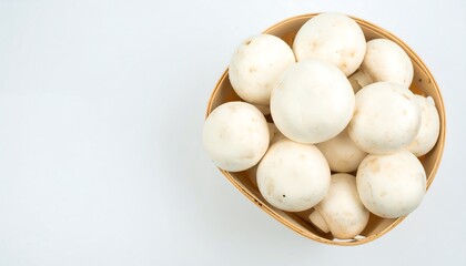 Fresh white button mushrooms fill a light wooden bowl against a plain white background.