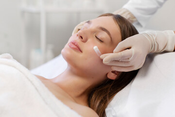 Spa salon treatments. Beautician applying cosmetic cream on woman face, lady receiving facial...