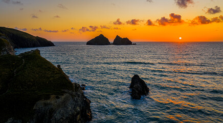 Twin rocks at Holywell Bay, Cornwall, during colorful sunset over the sea