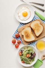 Breakfast spread featuring a sunny-side-up egg, toasted bread, fresh salad, and orange juice on a neatly arranged table.
