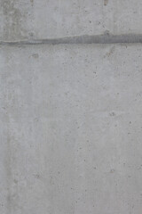 Close-up texture of a raw concrete wall. The surface shows natural imperfections, small holes, and subtle variations in color, typical of unfinished or industrial-style concrete.