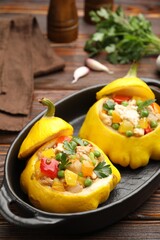 Tasty stuffed pattypan squashes in baking dish on wooden table, closeup
