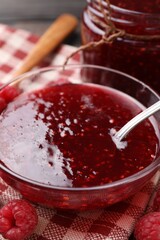 Sweet raspberry jam in glassware and berries on table, closeup