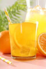 Refreshing soda water with orange slice in glass, jug and fresh fruits on pink wooden table, closeup
