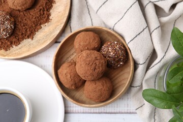 Delicious homemade candies with cocoa powder and coffee on white wooden table, flat lay