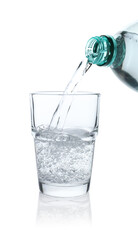 Pouring refreshing soda water from bottle into glass on white background