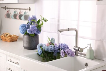 Bouquets of beautiful blue hortensia flowers in kitchen