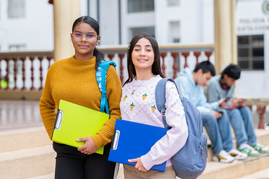 Latin american students holding folders and carrying backpacks