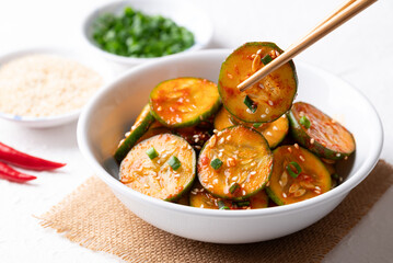 Korean cucumber salad (Oi muchim) in bowl with chopsticks on white background, Korean side dish