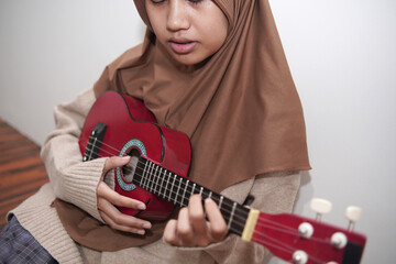 Asian muslim woman playing ukulele