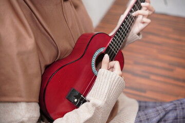 Asian muslim woman playing ukulele