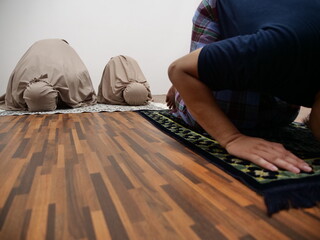 Asian muslim man doing shalat pray with his daughters, sujud