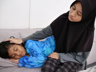 Asian muslim teenage girl put her little sister to sleep, love expression