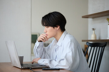 自宅で仕事をしているアジアの若い男性