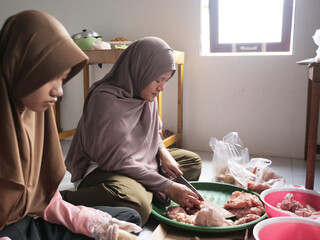 Indonesian muslim woman preparing meals in kitchen with her daughter, cooking traditional authentic asian food