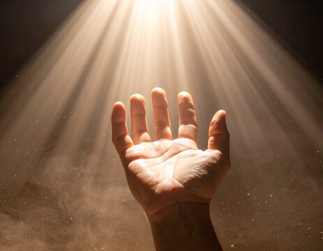 Mano extendida hacia un haz de luz brillante que entra desde arriba