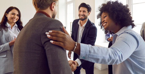 Diverse happy friends, companion congratulate hugging greeting each other gathered in office together, meeting, friendship between working people, hr cheerful communication for new colleague