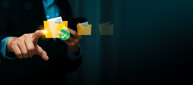 Businessman touching virtual folder icon with document and green check mark, representing document management system, secure digital file storage, data organization, and online archive workflow