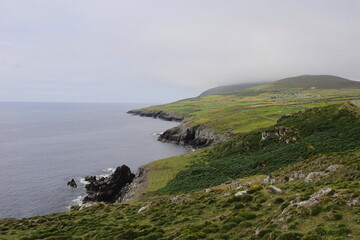 Scenic Wild Atlantic Way coastline with rugged cliffs, rolling green fields, and misty hilltop above the Atlantic Ocean, perfect for travel, tourism, and landscape photography themes